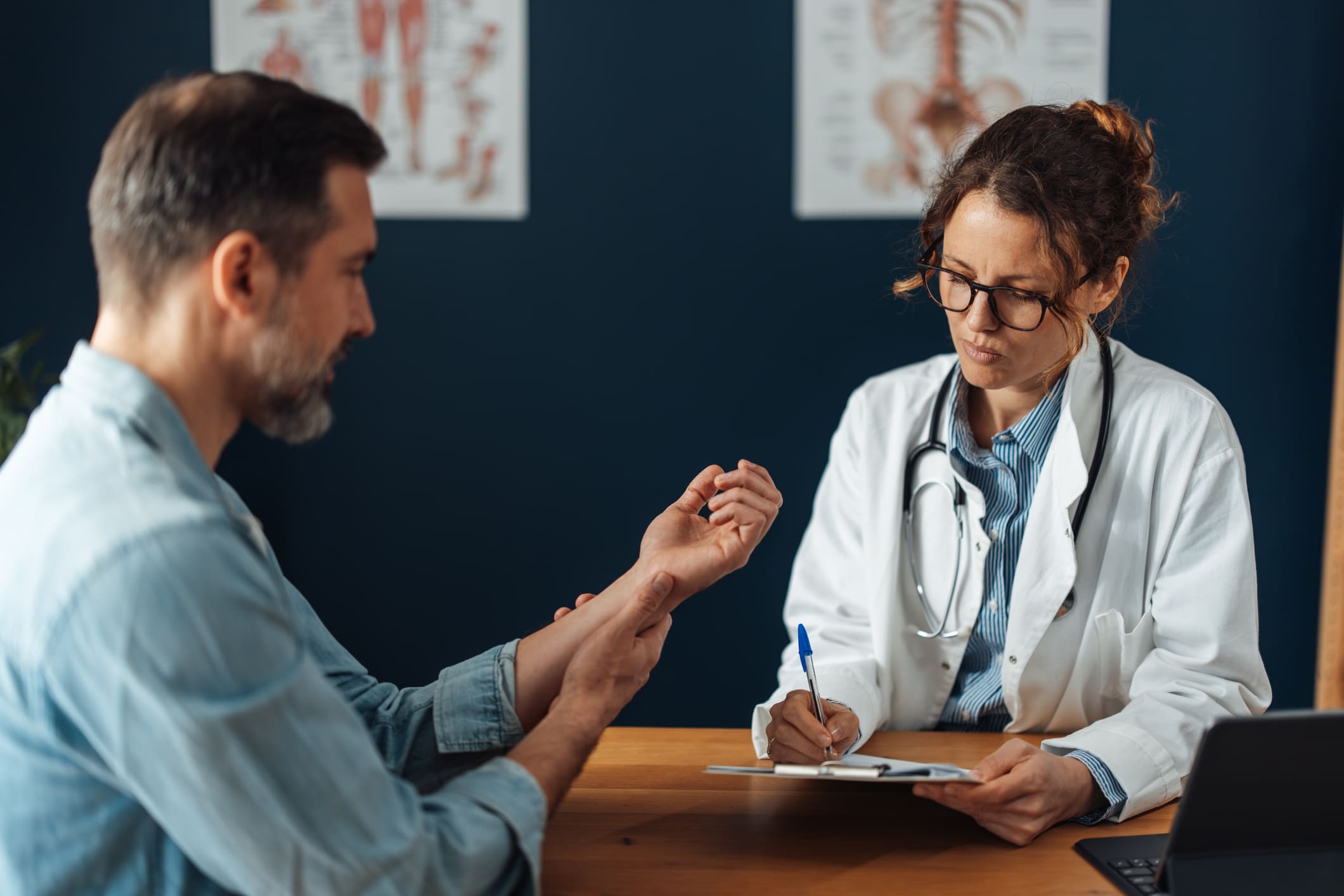 A doctor diligently notes details during a patient consultation, demonstrating active listening and the importance of documentation in effective healthcare communication.