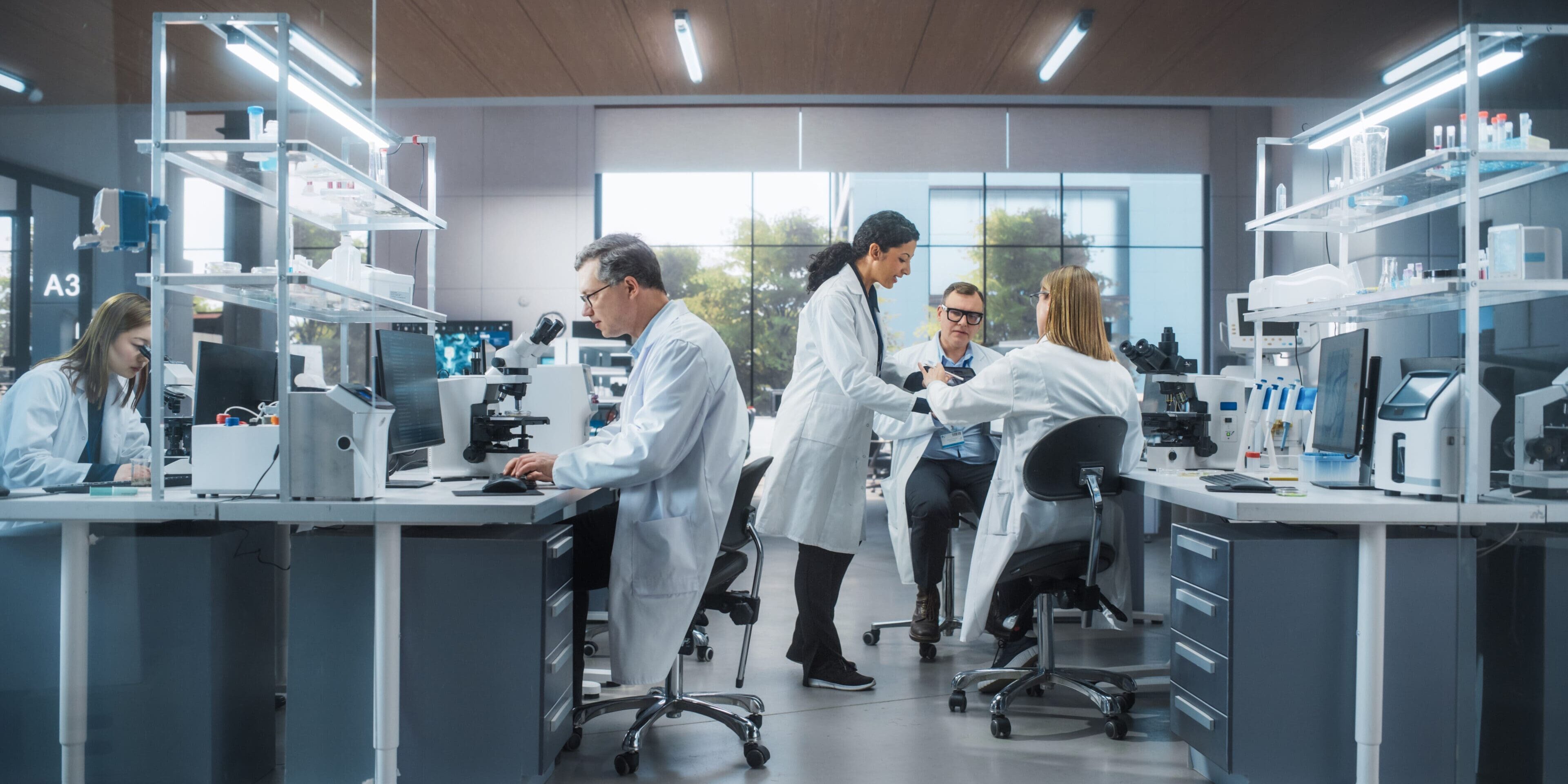 Three Scientists Discussing Latest Bioengineering Discoveries and Sharing Research Data on Vaccine Efficacy. Diverse Male and Female Colleagues Working in a Modern Medical Research Center